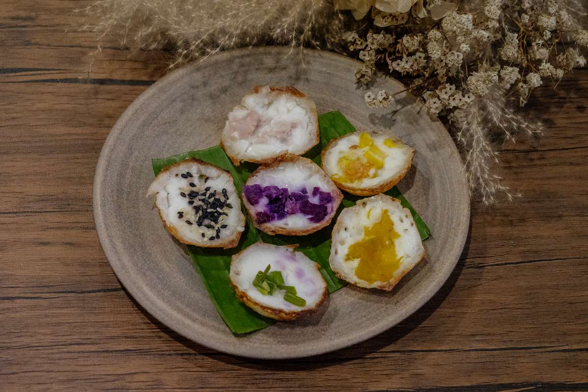 Die schalenförmigen Leckerbissen Khanom Krok (ขนมครก) hier auf einem rustikalen Steinteller präsentiert