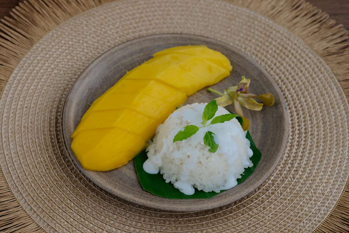 Mango Sticky Rice (ข้าวเหนียวมะม่วง), das bekannteste Thai Dessert auf einem Steinteller angerichtet.