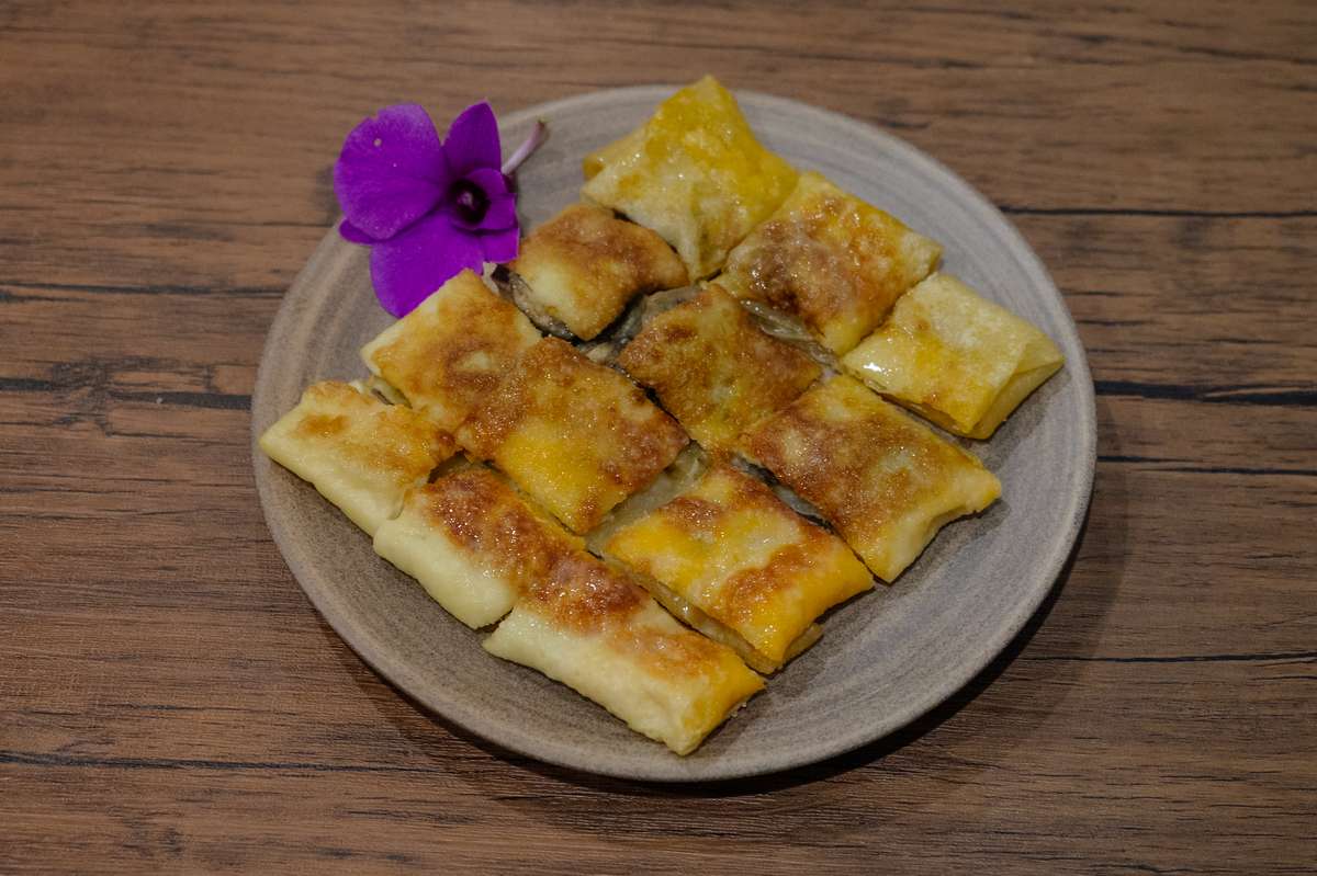 Die Teigspezialität Roti (โรตี) mit Bananen gefüllt und mit Kondensmilch übergossen