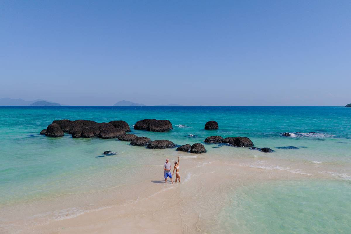 Vulkangestein im türkisfarbenen Meer auf der Insel Koh Kham in Thailand