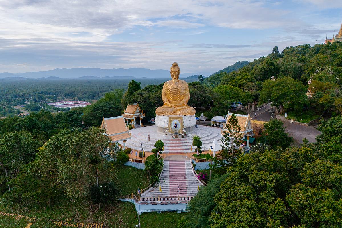 Ein sitzender, goldener Buddha am Eingang zum Phra Mahathat Chedi Phakdee Prakat Tempel