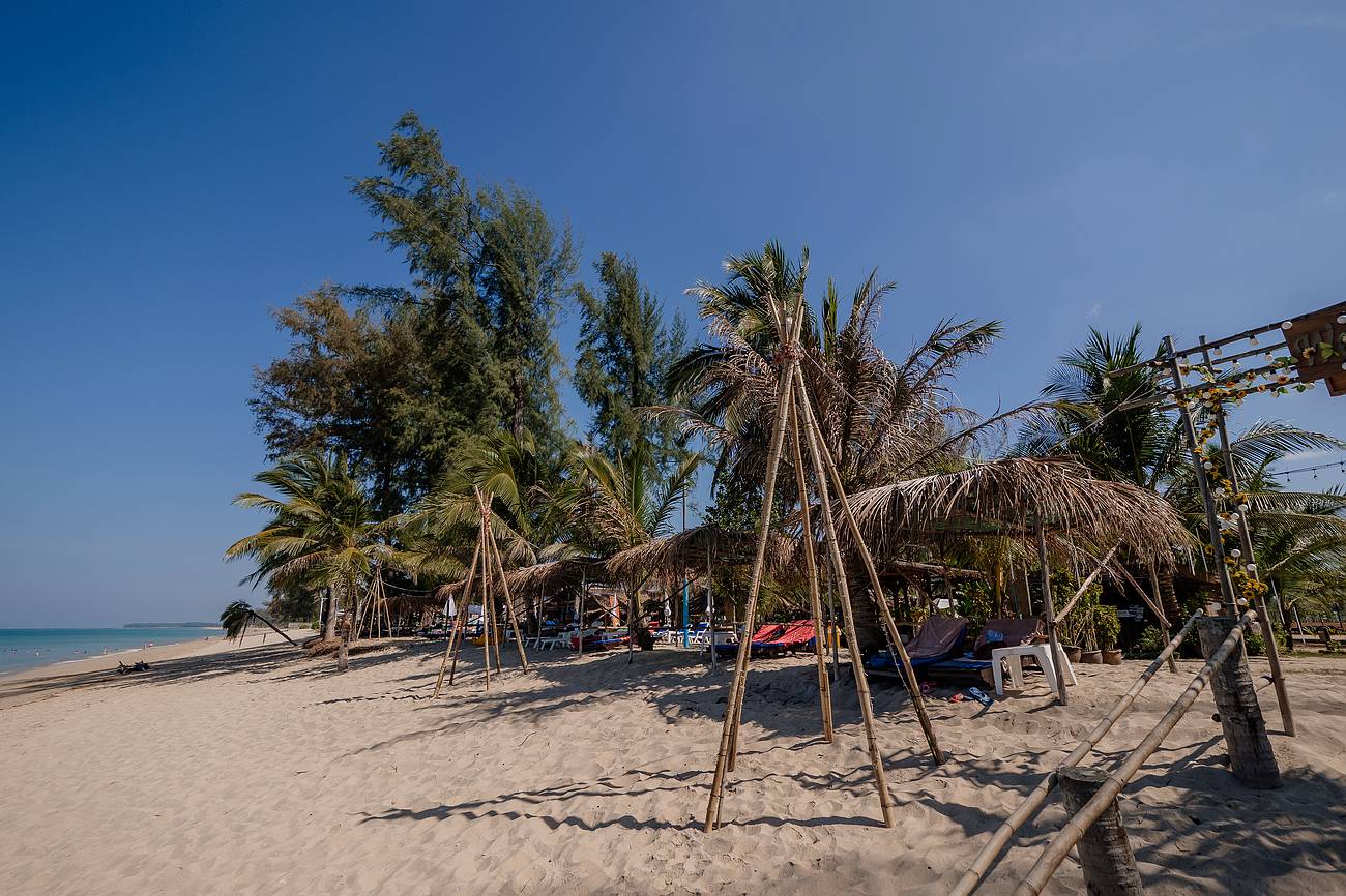 Ruhiger Sandstrand in Khao Lak mit Palmen und Liegen – trockenes, warmes Wetter ideal zum Entspannen