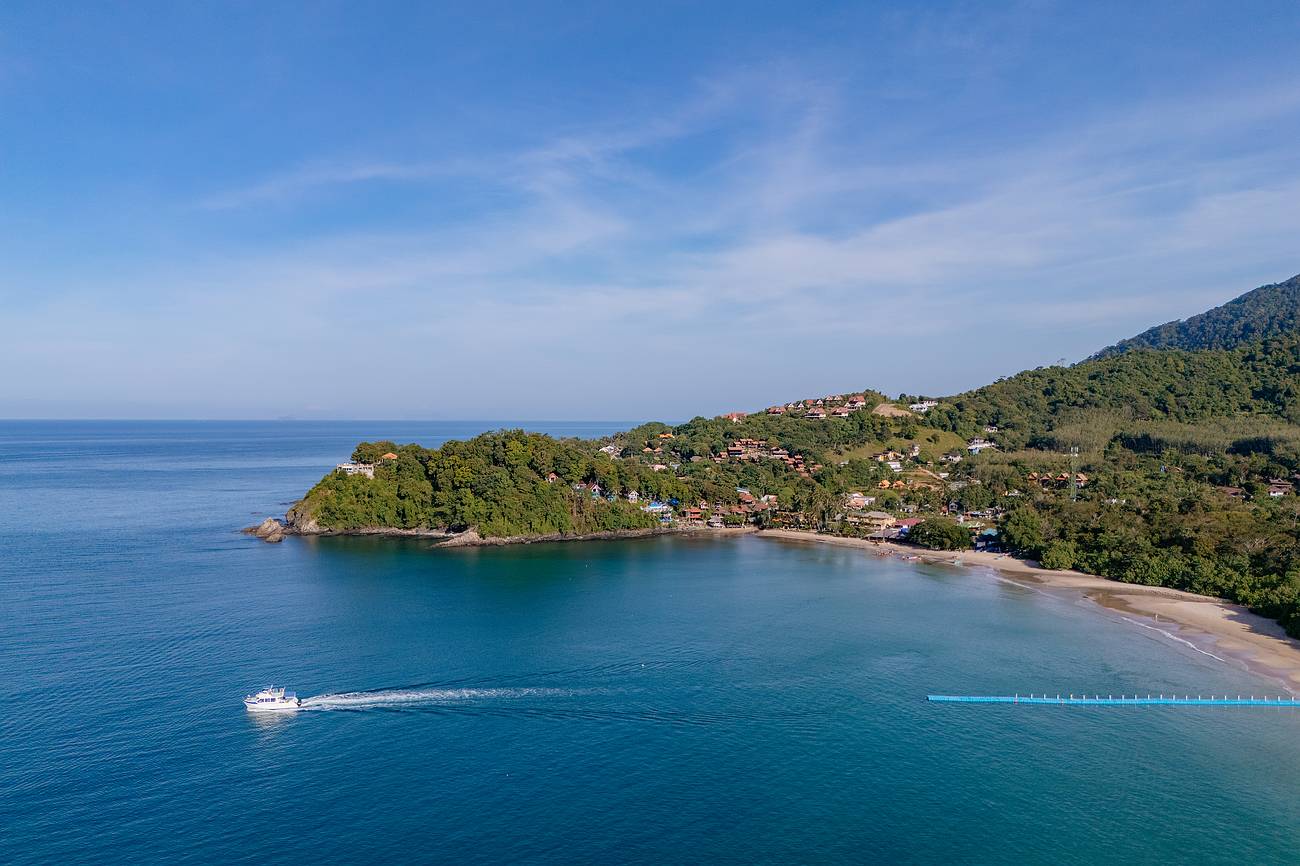 Boot vor ruhiger Küste mit türkisfarbenem Wasser – ideales Wetter mit wenig Wind und klarem Himmel während der Trockenzeit