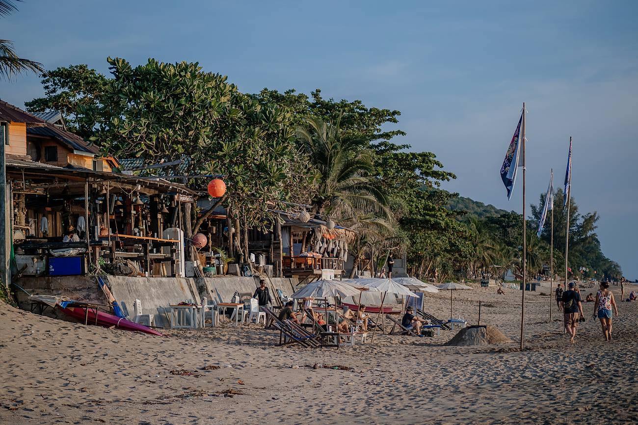 Belebter Strand mit Restaurants und Bars auf Koh Lanta bei warmem, sonnigem Klima während der besten Reisezeit von Dezember bis April